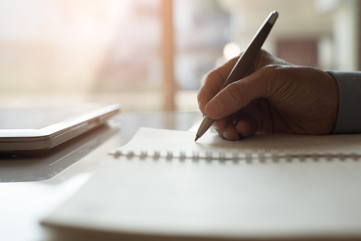a person writing on a piece of paper with a pen.