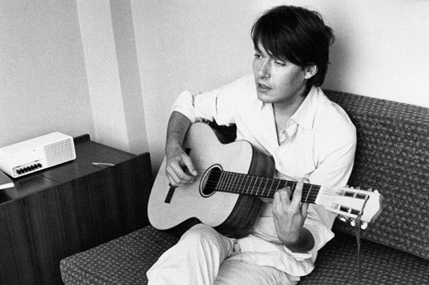 a man sitting on a couch playing a guitar.