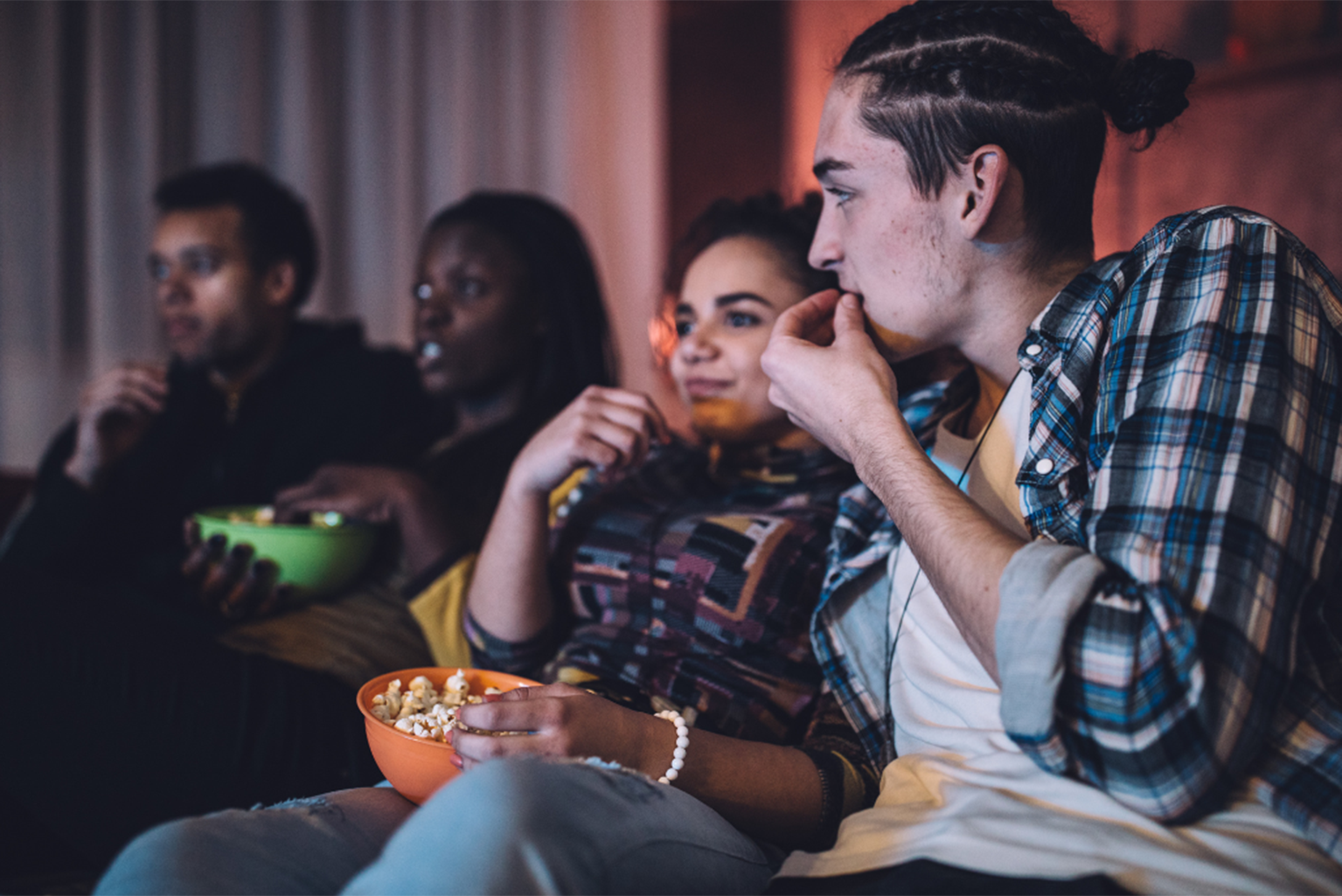 a group of people sitting on a couch watching a movie.